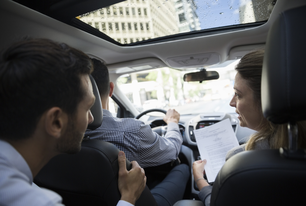 Business People Carpooling And Discussing Paperwork In Car